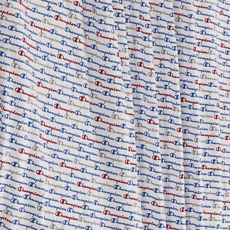 Close-up of the super-soft Printed Microfiber Sheet Set by Champion, featuring a repeating blue and red Champion logo pattern on a white background. Light wrinkles and folds in the fabric enhance the cozy appeal of these branded sheets.