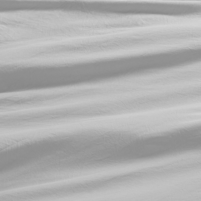 Close-up of white, slightly wrinkled fabric with soft shadows and gentle folds, creating a subtle textured pattern across the surface—evoking the smooth comfort of the Champion Elastic Logo Microfiber Sheet Set.
