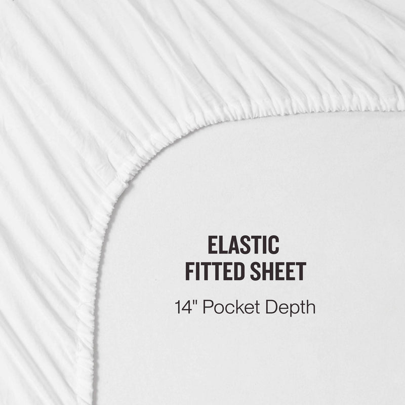 Close-up of a white elastic fitted sheet with text that reads “ELASTIC FITTED SHEET 14” Pocket Depth.“ The sheet, from the Champion Embroidery Patch Microfiber Sheet Set, is stretched over a corner to demonstrate its fit and pocket depth. A signature embroidered Champion patch highlights this athletic-inspired bedding collection.
