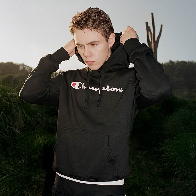 Person wearing a black Champion hoodie in an outdoor setting