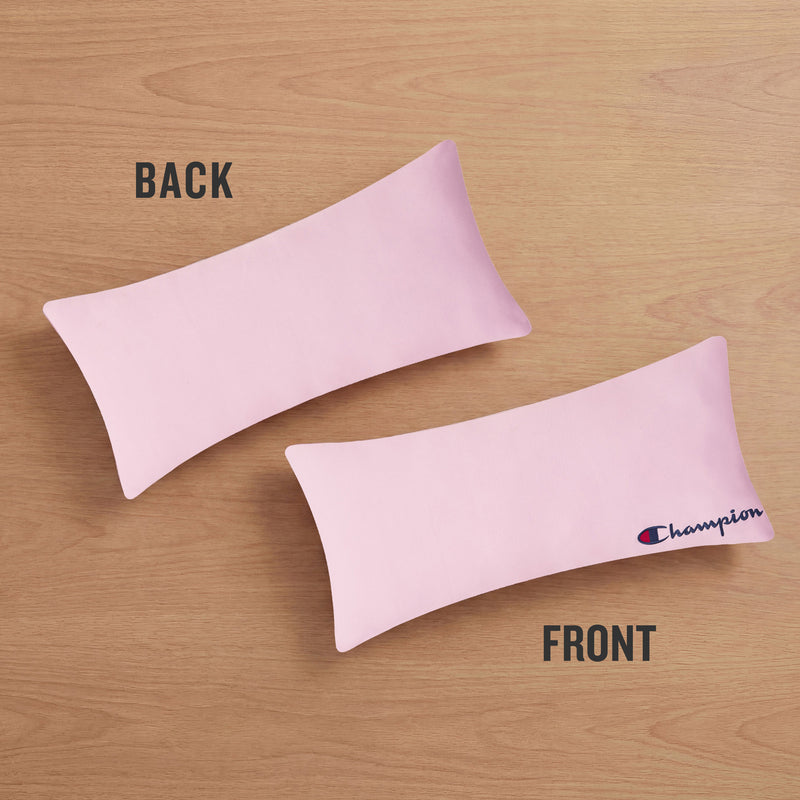 Two pink rectangular Jersey Body Pillows by Champion rest on a wooden surface. One is turned to display the plain back, while the other shows the front featuring the Champion logo embroidered on the right side—an ideal athletic accent for your space. Labels above each pillow read BACK and FRONT.