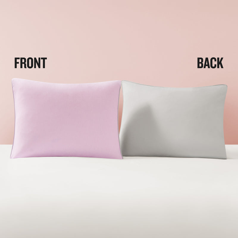 Two rectangular pillowcases are displayed side by side; the left one is light pink labeled “Front,” and the right one is light gray labeled “Back,” set against a pale pink background—perfect for pairing with Champion’s Reversible Solid Jersey Comforter Sets or any reversible bedding collection.