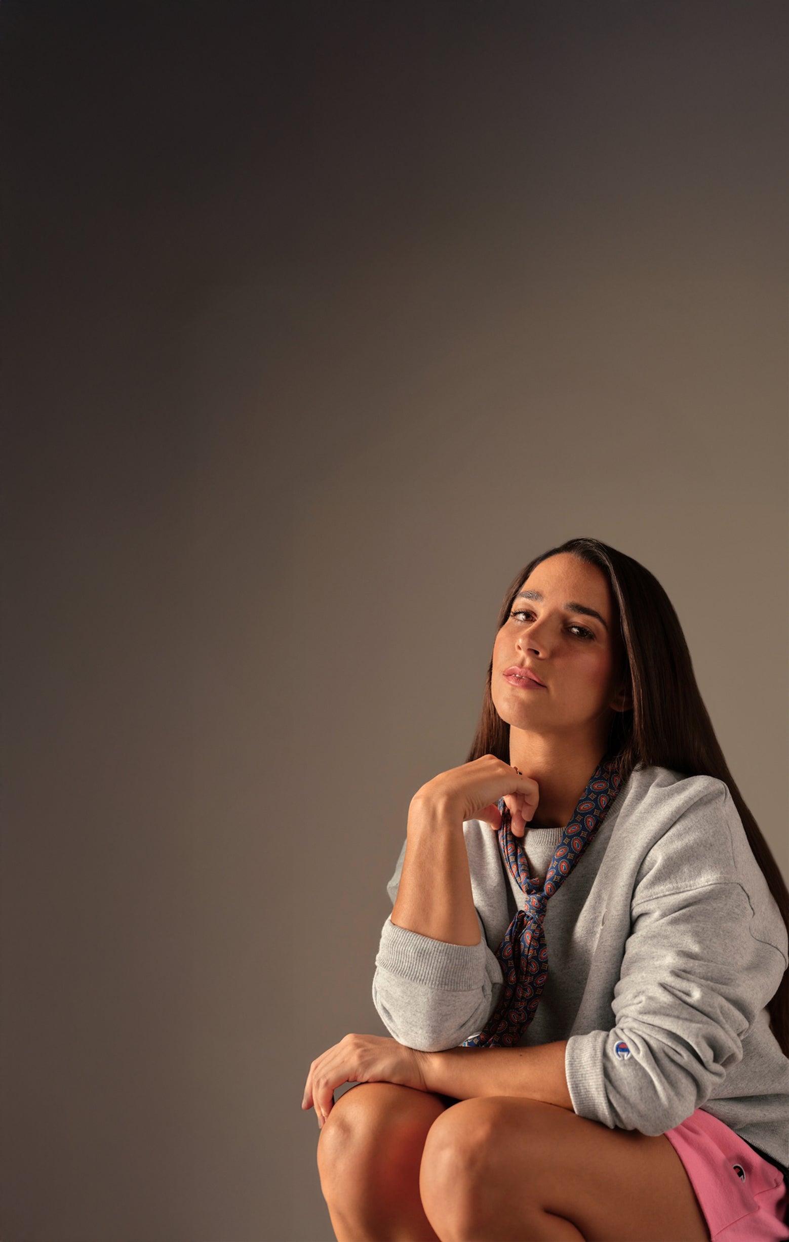 Woman sitting on a stool against a plain background