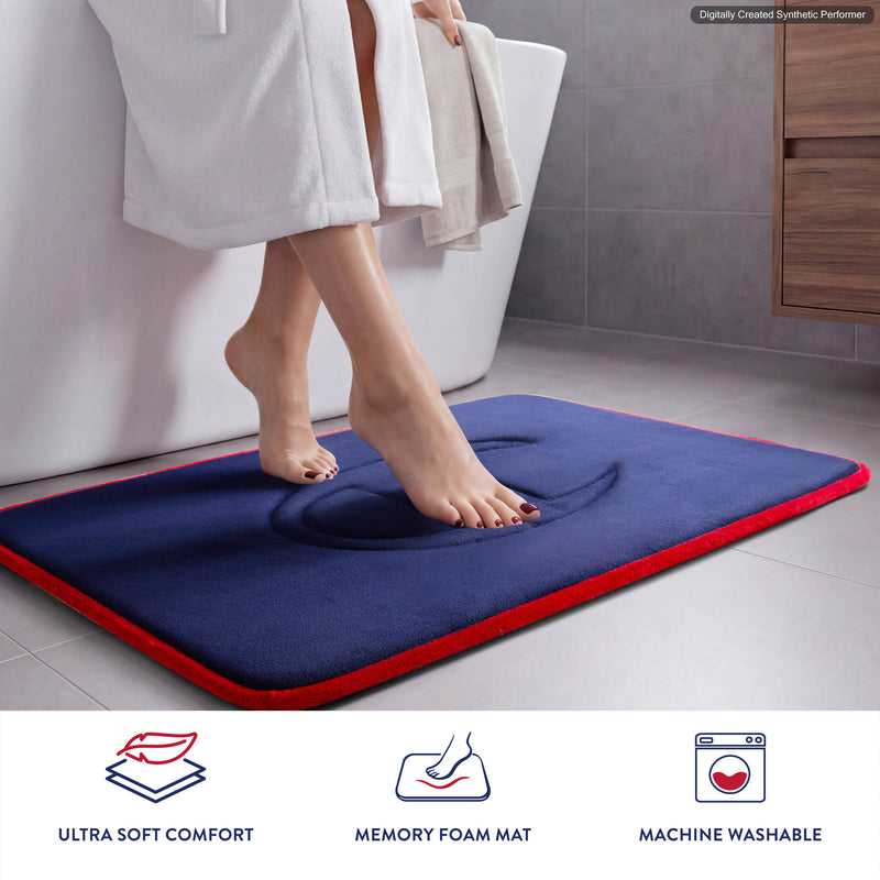 A person steps onto a Champion Quilted Logo Memory Foam Bath Mat in blue with bold red edges in the bathroom. Icons below showcase its ultra-soft comfort, premium memory foam construction, and easy machine washability—making it a true Champion choice for everyday luxury.