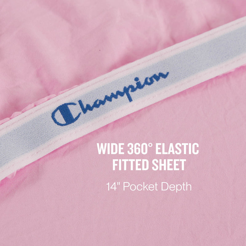 A close-up of a pink Champion Peak Comfort Microfiber fitted sheet with a wide 360° elastic band showcases the athletic bedding, featuring text stating WIDE 360° ELASTIC FITTED SHEET 14” Pocket Depth. Part of the Champion Peak Comfort Microfiber Sheet Set, these deep pocket sheets ensure a secure and comfortable fit for your mattress.