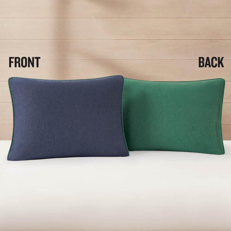 A rectangular pillow with a navy blue front and a green back is displayed side by side to show both colors—an ideal match for your Premium Reversible Solid Jersey Comforter Set by Champion or any favorite reversible comforter. The background features light wood paneling, with the words FRONT and BACK labeling each side.