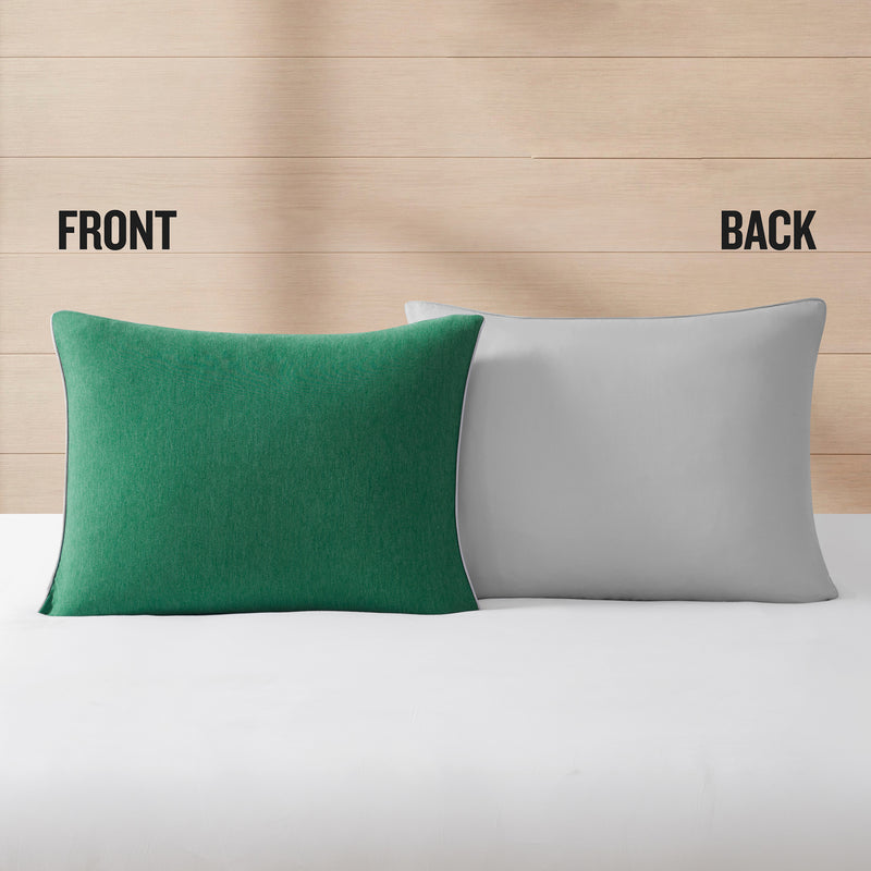 Two pillows from the Champion Reversible Solid Jersey Comforter Sets rest on a white surface against a wood background. The left pillow is green and marked FRONT, while the right pillow is gray and marked BACK, highlighting the reversible design that brings added versatility to any athletic bedding setup.