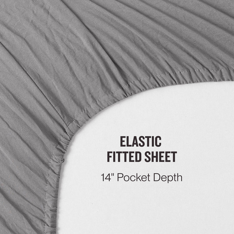 A gray fitted sheet from the Champion Embroidery Patch Microfiber Sheet Set is partially covering a mattress, displaying the text: ELASTIC FITTED SHEET 14 Pocket Depth. This stylish microfiber sheet set from Champion provides both comfort and durability for a restful night’s sleep.