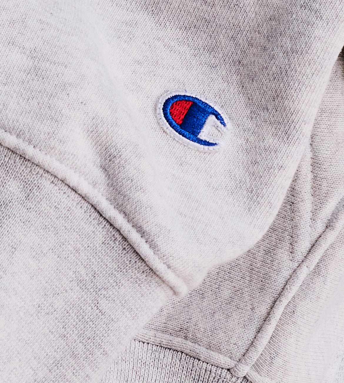 Close-up of a gray sweatshirt with a Champion logo on the chest.