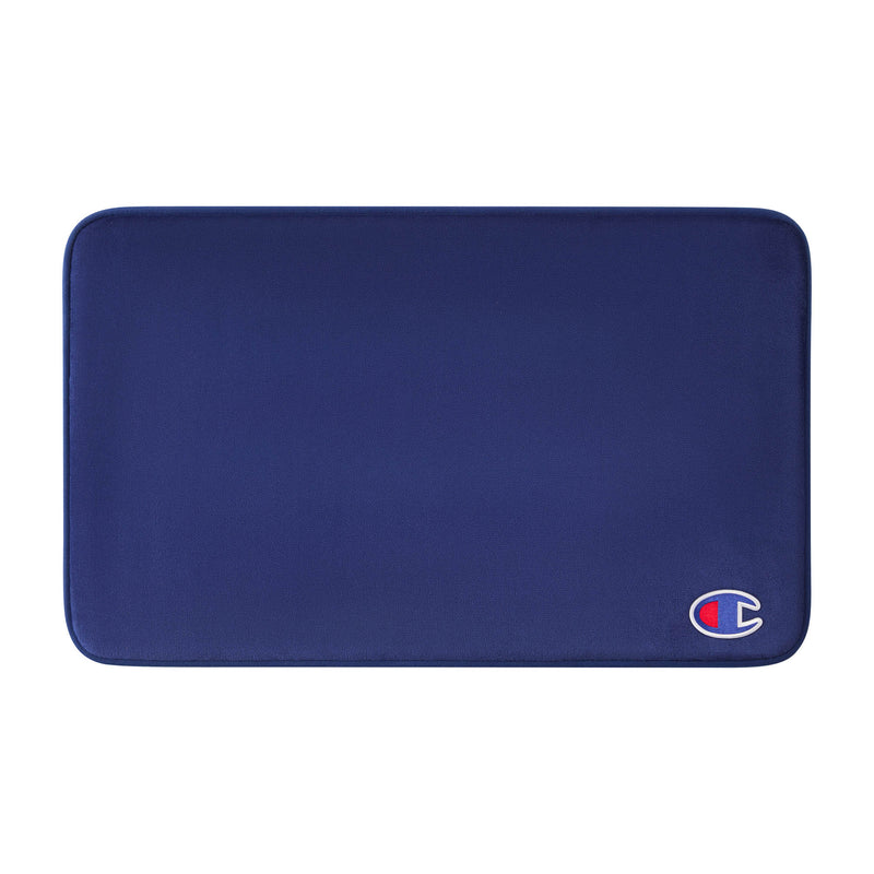 A rectangular, dark blue Logo Patch Memory Foam Bath Mat by Champion features rounded corners and a small Champion logo patch in the lower right corner. Its soft, smooth surface provides a skid-resistant finish for added safety.