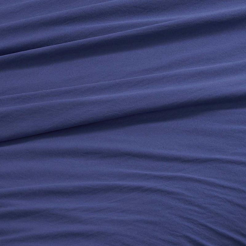 A close-up of the Champion Elastic Logo Microfiber Sheet Set in blue, featuring gentle diagonal folds and a soft texture that exudes smoothness and comfort—beautifully conveying the inviting appeal of this microfiber bedding.