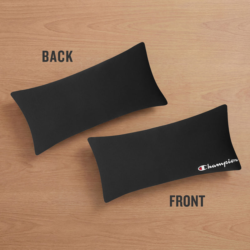 Two black rectangular fabric pieces rest on a wooden surface; one labeled BACK is plain, while the other labeled FRONT features a small white and red Champion logo in the corner—making it ideal as an athletic accent or body pillow cover. The Champion Jersey Body Pillows are crafted from soft jersey knit, delivering comfort and sporty style.
