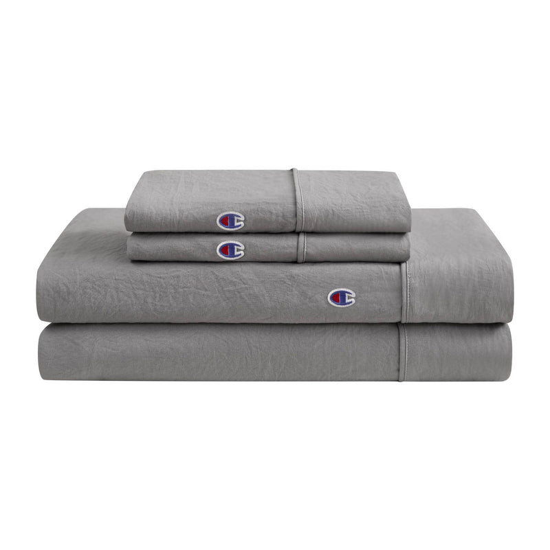A neatly folded stack of Champion Embroidery Patch Microfiber Sheet Set in gray, featuring bedding sheets and pillowcases adorned with the signature blue, red, and white embroidered C logo. This set offers comfort and iconic Champion style for your bed.