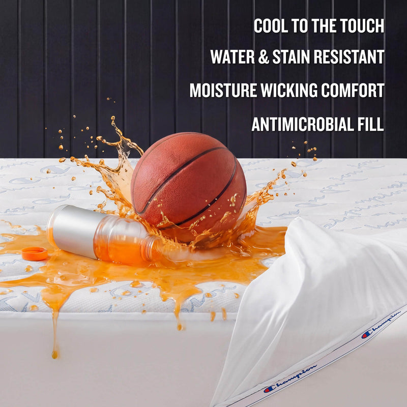 A basketball sits next to a spilled orange drink on a mattress topped with a pillow, showcasing the Champion Cooling Knit Mattress Pad—crafted for cool-to-the-touch comfort with premium cooling technology, featuring a stain-resistant and water-repellent surface, moisture-wicking design, and advanced antimicrobial fill.